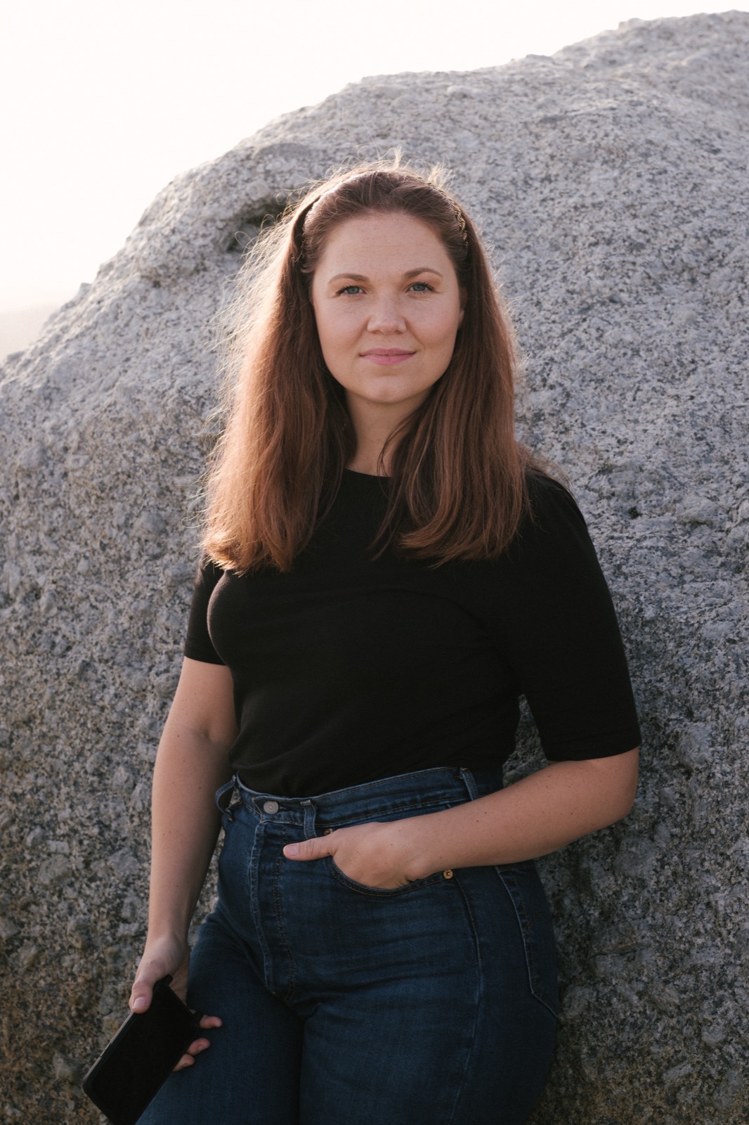 Portrait of Jane in a black tee leaning against a granite rock