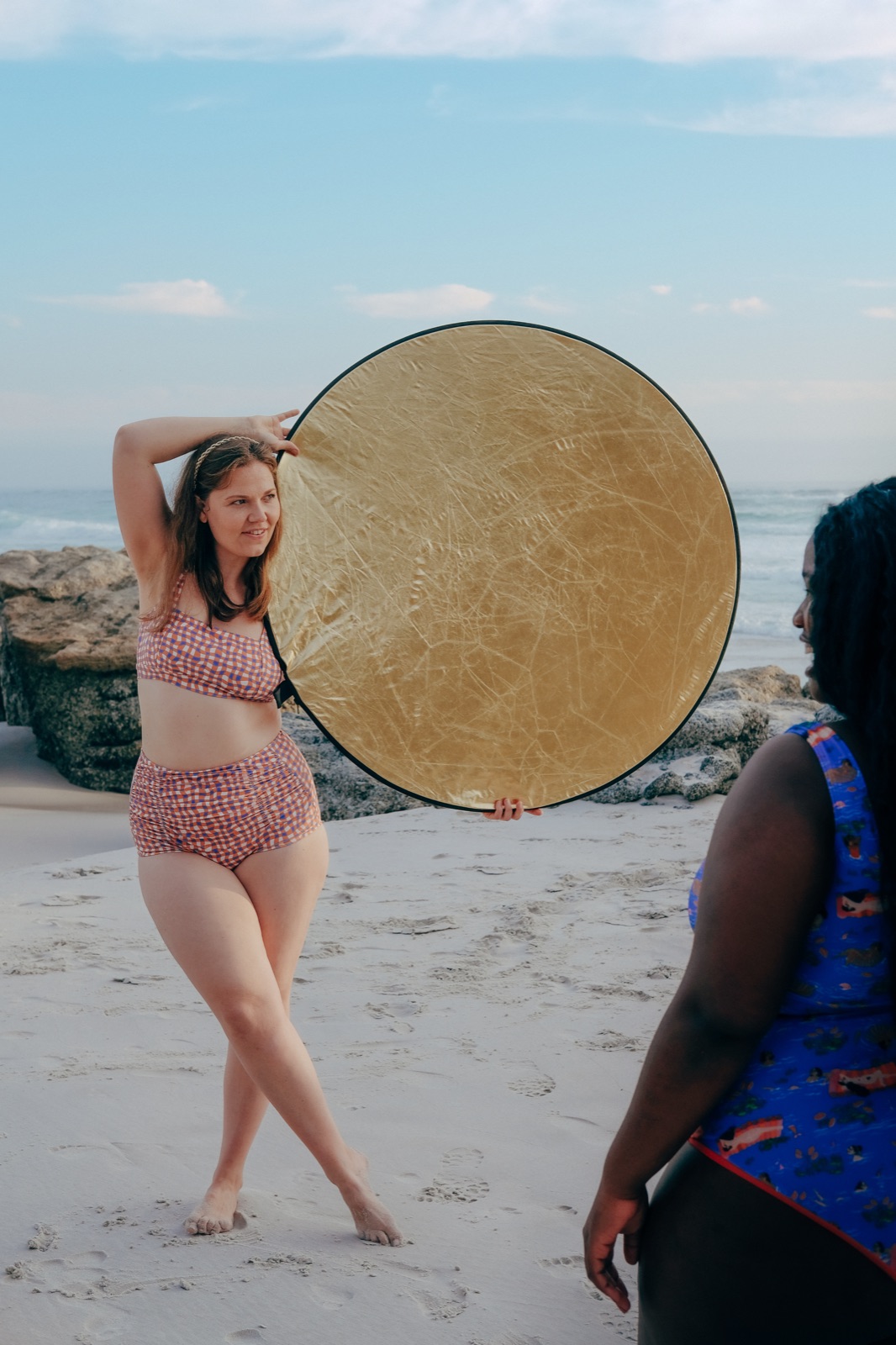 Jane holding a gold reflector on the beach, photographing a subject